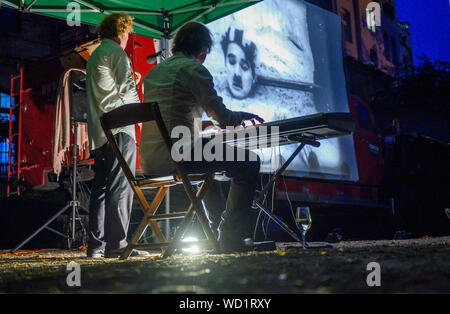 Waren, Allemagne. Août 28, 2019. Les musiciens Tobias Rang (piano) et Stephan Gunthard (violon) jouer live pour présenter différents films muets. Voyager avec leur cinéma, un ancien pompier Magirus Deutz construit en 1969, les deux musiciens étudiés voyager dans toute l'Allemagne. Tous les genres de films muets sont indiquées - à partir de leur création en 1895 à la fin de l'époque du film muet autour de 1930. Credit : Jens Büttner/dpa-Zentralbild/dpa/Alamy Live News Banque D'Images