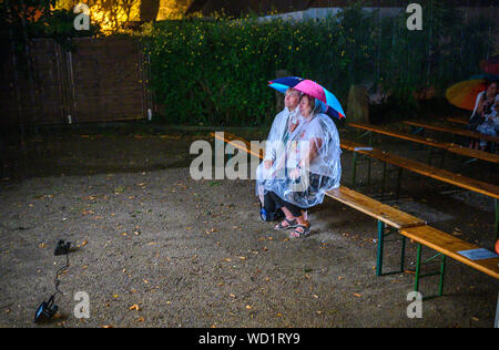 Waren, Allemagne. Août 28, 2019. Les spectateurs assis dans la pluie en face de l'ancienne brigade incendie Magirus Deutz, construit en 1969, montrant vieux films muets. Les deux musiciens Rang et Stephan voyagent sur toute l'Allemagne avec leurs voyages cinéma, une ancienne caserne de pompiers. Tous les genres de films muets sont indiquées - à partir de leur création en 1895 à la fin de l'époque du film muet autour de 1930. Credit : Jens Büttner/dpa-Zentralbild/dpa/Alamy Live News Banque D'Images