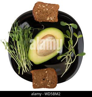 Petit déjeuner sain. Les choux verts micro, d'avocat et de pain sur une plaque noire isolé sur fond blanc. Banque D'Images