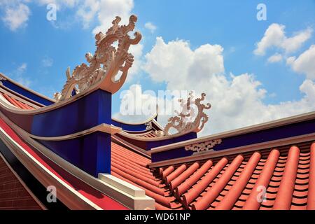 Toit de temple Chinois de Singapour avec des sculptures en pierre et de conception architecturale forte contre le ciel bleu avec des nuages Banque D'Images