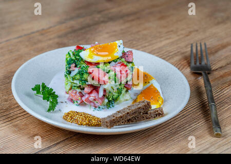 Délicieux avec la salade de brocoli, tomate, oignon et œuf dur à la crème dans une assiette sur fond de bois. L'alimentation saine, Close up Banque D'Images