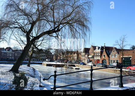 Hoorn, Noord-Holland / Pays-Bas - Mars 11, 2012 : l'eau gelée et montrer sur canal et vieux bâtiments traditionnels en briques avec des toits de tuile à sunny winte Banque D'Images