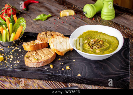 L'hoummos aux épinards, avocat et graines de citrouille dans un bol sur une planche en bois et bruschetta, cuisine orientale , l'orientation horizontale Banque D'Images