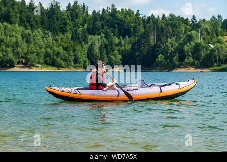 Jeune femme active en kayak Kayak gonflable sur le lac Lokve, dans la région de Gorski Kotar, Croatie. L'expérience d'aventure sur une belle journée ensoleillée. Banque D'Images