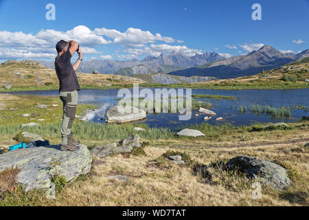 SAINT-Sorlin, FRANCE, le 9 août 2019 : Photographe tire un beau paysage de montagne sur une rive du lac. Banque D'Images