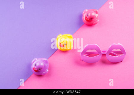 Funky coloré de l'été mise à plat avec les articles drôle - canards en caoutchouc, lunettes de forme de lèvre. Rose et violet fond duotone. Banque D'Images