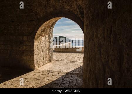 Magnifique photo de la porte en briques cintrées avec vue d'une mer et d'une montagne boisée Banque D'Images