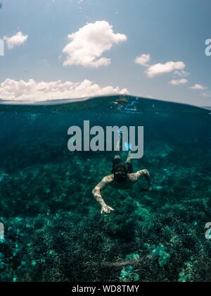 Prise de vue verticale d'un homme nageant sous l'eau avec le ciel l'arrière-plan Banque D'Images