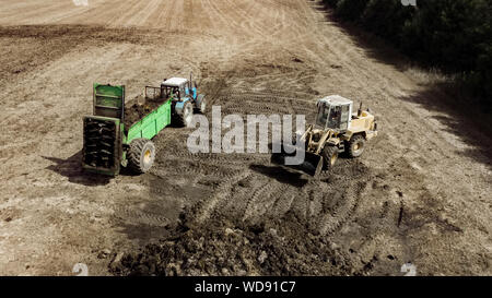 Drague avec un peu de fumier remorque chargement pour le champ de la fécondation. Machine agricole pour la fertilisation. La bouse de vache Banque D'Images