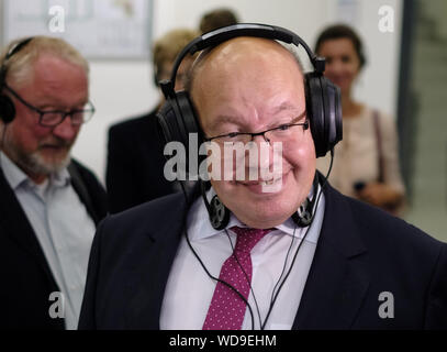 Wedemark, Allemagne. Août 29, 2019. Peter Altmaier (CDU), Ministre fédéral de l'économie, est en train de tester le casque HD800 chez Sennheiser. Altmaier visites moyennes entreprises en Basse Saxe et Rhénanie du Nord-Westphalie durant son voyage de trois jours, également d'envoyer un signal aux entreprises de taille moyenne. Il avait été fortement critiqué par des associations commerciales, en partie parce que les petites et moyennes entreprises n'a guère joué un rôle dans sa stratégie industrielle. Credit : Ole Spata/dpa/Alamy Live News Banque D'Images