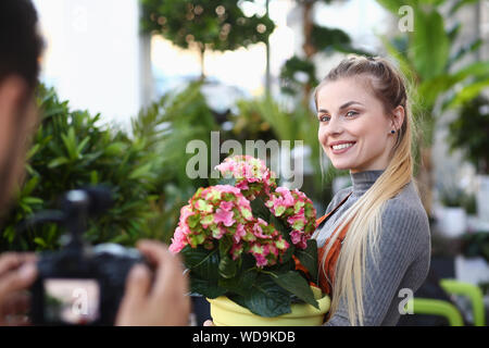 Vlogger heureux posant avec fleur à l'homme de l'appareil photo Banque D'Images