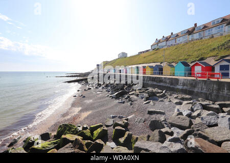 Cabines colorées le long du front de mer de Sheringham sur une journée ensoleillée avec un ciel bleu. Banque D'Images