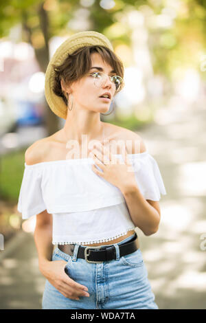 Young woman wearing straw hat montrant ses dents tout en marchant dans Green Park Banque D'Images