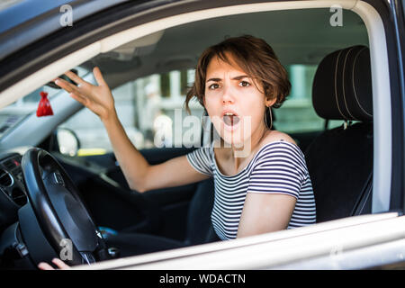 Femme mécontent de conduire la voiture et crier à quelqu'un Banque D'Images