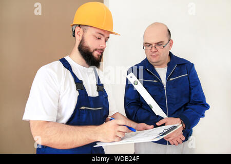 L'ingénieur, l'entrepreneur et le chef de projet avec son collègue, travailleur de la construction, d'un bricoleur et builder est la mesure de mur à l'aide d'un niveau à l'outil. Banque D'Images