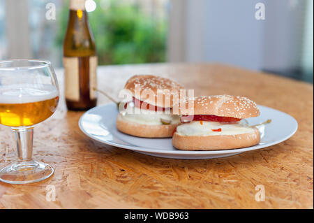 Home made burgers au fromage sur la plaque et le verre de bière. Image horizontale. Banque D'Images