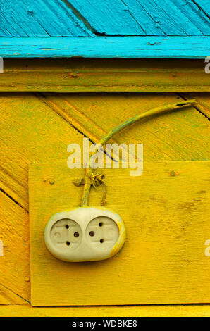 Prise électrique à l'ancienne avec un fil sur un mur en bois jaune-bleu closeup Banque D'Images