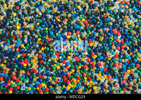 Colorant polymérique colorés industriels. Granules de plastique. Colorant pour les matières plastiques. Pigment dans la texture de fond des granules de polyéthylène en plastique. Banque D'Images