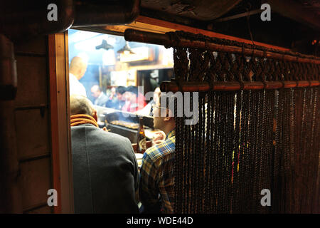 Les gens prendre des boissons et des aliments de rue à l'intérieur d'un petit pub dans Omoide Yokocho alley. Banque D'Images