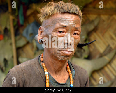 À la retraite, vieux guerrier Naga Konyak et ex-chasseur avec tribal tatouage distinctif du visage et les cerfs cornes dans son lobe de pose pour la caméra. Banque D'Images