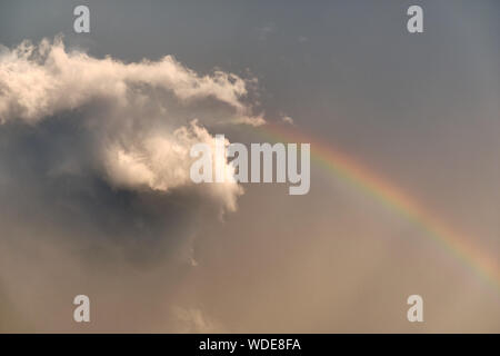 De beaux paysages dans le ciel à la suite de précipitations avec un nuage gris au soleil et un arc-en-ciel sur un ciel gris Banque D'Images