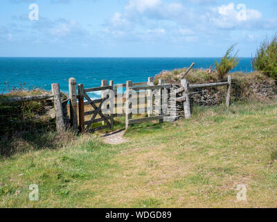 Une porte en bois s'embrasser sur le south west coast path près de Cornwall Porthcothan UK avec vue sur la mer Banque D'Images