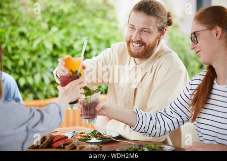 Happy friends holding cocktails de fruits et le grillage avec eux au cours de leur réunion de cafe Banque D'Images