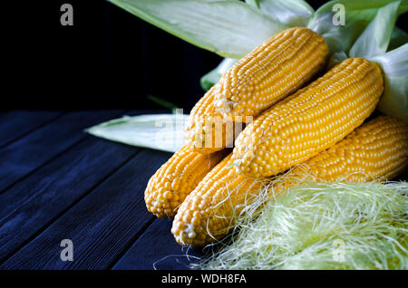 Maïs bonduel jaune juteux frais avec des feuilles vertes se trouve sur la table en bois Banque D'Images