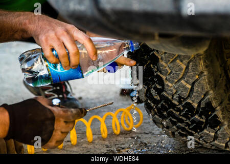 Réparation de pneus de type expédition sur la route de la soie à Murghab, Tadjikistan. Le compresseur, la bouteille d'eau, le semoir et un fil de caoutchouc vulcanisable sont suffisants pour que le pneu dure encore 1 000 kilomètres sur des routes en gravier Banque D'Images