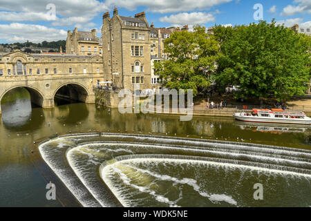 BATH, ANGLETERRE - Juillet 2019 : vue grand angle de l'Pulteney Weir en forme de fer à cheval sur la rivière Avon et Pulteney Bridge dans le centre de Bath. Banque D'Images