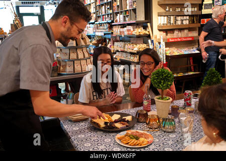 Madison, WI USA. Jul 2018. Les jeunes dames asiatiques obtenir une assiette de charcuterie de visite à l'un des membres du personnel courtois et serviable. Banque D'Images