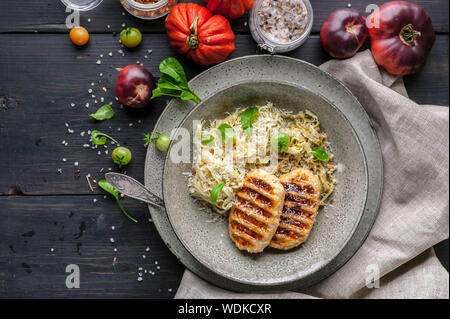 Burgers de poulet grillé avec des spaghetti avec sauce pesto classique, paprika doux, tomates et roquette fraîche. Vue d'en haut Banque D'Images