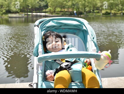 Cute smiling baby girl sitting in turquoise poussette par Lake Shore Banque D'Images