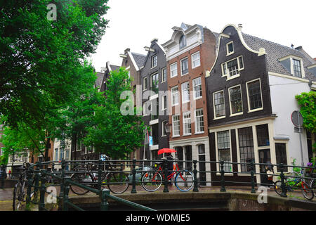 Des vélos sur un pont au-dessus du canal d'Amsterdam, Pays-Bas. Vue pittoresque de bâtiments typiquement européen et des vélos par temps couvert 24. Eco-friendly Banque D'Images