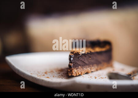 Tranche de gâteau au chocolat noir riche végétalien sur une plaque blanche à l'hôtel. Libre, le minimalisme concept photograohy alimentaire. Selective focus, flou Banque D'Images