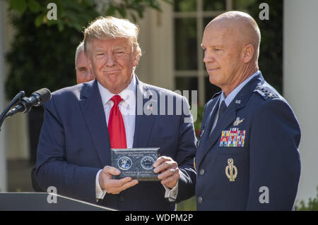 Washington, District de Columbia, Etats-Unis. Août 29, 2019. Le président DONALD TRUMP, gauche, détient un moment présenté par le général John W. ''JAY'' RAYMOND, commandant de l'Air Force Space Command, droite, au cours d'une cérémonie annonçant la création de l'US Space Command dans la roseraie de la Maison Blanche. La commande de l'espace sera le principal responsable de l'agence militaire pour la planification et l'exécution des opérations dans l'espace et sera un pas vers l'établissement d'un espace de travail comme un nouveau service militaire. Credit : Ron Sachs/CNP/ZUMA/Alamy Fil Live News Banque D'Images