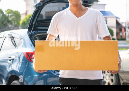 De gros plan homme asiatique heureux offrir boîte en carton à des clients par voiture privée. Les modes de vie des gens d'affaires et de l'occupation concept. Jeune homme courie Banque D'Images