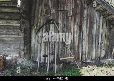 Très vieux, rouillé et sale de travail Outils de jardin rural (houe, râteau, bêche, faux, hache, pitchfork) près de la grange de boiseries en campagne durant l'été Banque D'Images