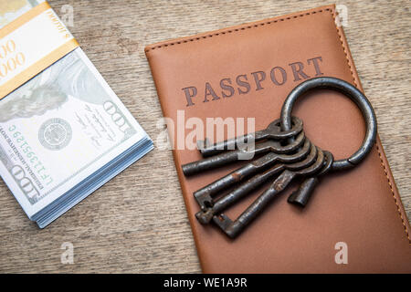 Bande de différentes clés, passeport et de l'argent sur un fond de bois Banque D'Images