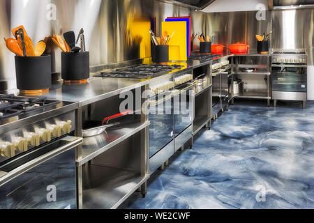 Nouvelle marque moderne cuisine entièrement équipée avec une ligne de fours, tasse et ustensiles de tables à repasser, le long de la parois en aluminium brossé prêt à cuire. Banque D'Images