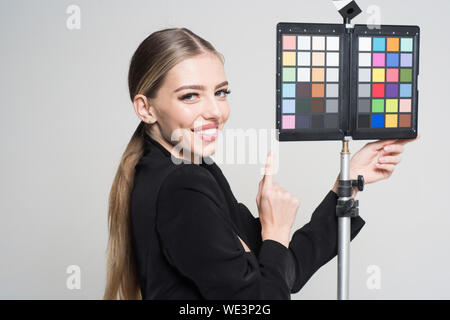 Le jeune photographe au pointage de la carte contrôleur de couleur, tout en travaillant en studio. Fille en costume officiel se prépare pour la séance photo. Concept de photographie. Bro Banque D'Images