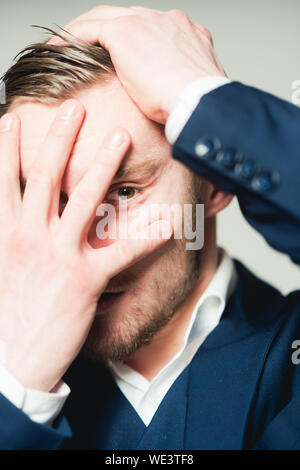 Libre à l'homme par ses doigts et en tirant ses cheveux en arrière avec l'autre main isolé sur fond gris. Banque D'Images