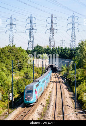 Un double-decker TGV Duplex TGV Ouigo en livrée est entrée dans un tunnel sous une rangée de tours de transmission sur la LGV Atlantique Railway. Banque D'Images