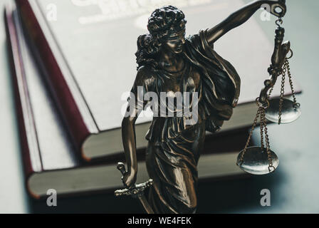 Statue de la figure de la Justice tenant une épée et des balances high angle contre livres de droit en cour symbolique de la loi Banque D'Images