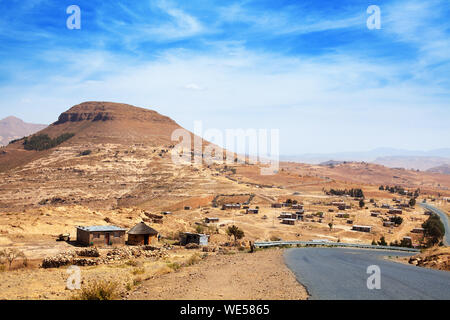 Montagnes du Drakensberg paysage Highland Valley vue panoramique, d'un bleu fond de ciel ensoleillé, route et village, le Lesotho, le sud de l'Afrique voyage Banque D'Images