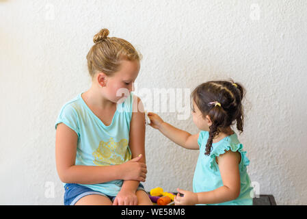 Concept de vaccination. Enfants jouant médecin. Peu de tout-petit médecin vaccinant cute adolescentes en clinique. Banque D'Images