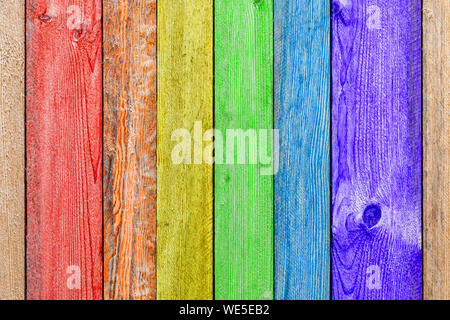 Close-up d'un mur ou une clôture en bois arc-en-ciel peint un temps très long et la peinture écaillé. Fond amusant pour les enfants et un décor design. Banque D'Images