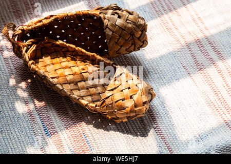 Vieux russe des sandales faites de l'écorce. Chaussures d'écorce de bouleau russe ancien traditionnel, sur un vieux mensonge chaussures tapis traditionnel au soleil. Banque D'Images