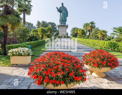 Fleurs colorées avec l'imposant Colosse de San Carlo Borromeo, Arona, Italie dans l'arrière-plan Banque D'Images