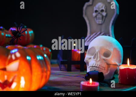 Crâne effrayant sous la lumière des bougies sur une table en bois pour Halloween. Spooky pumpkin. Banque D'Images